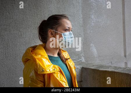 Europäisches Mädchen, das mit sars-cov-2-Virus in einer medizinischen Schutzmaske im Gesicht infiziert ist Stockfoto