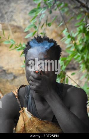 Hadza Mann rauchen von einem traditionellen tonpfeifen fotografiert in der Nähe von Lake Eyasi, Tansania, Afrika Stockfoto