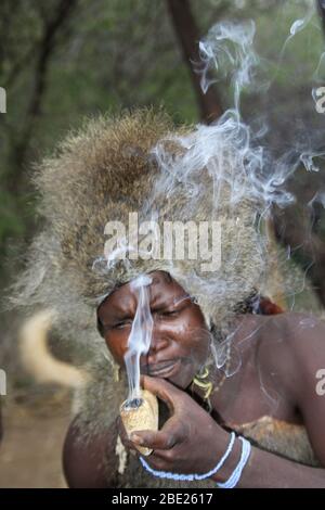 Hadza Mann rauchen von einem traditionellen tonpfeifen fotografiert in der Nähe von Lake Eyasi, Tansania, Afrika Stockfoto