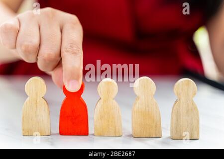 Abbildung im Konzept des Personalmanagements. Die rote Holzfigur wurde aus ihrer Gruppe herausgeholt. Rote Holzfigur, wie der vom Kandidaten ausgewählt wird, Stockfoto