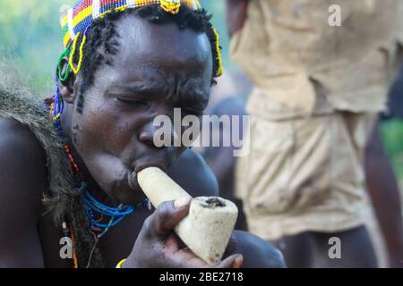 Hadza Mann rauchen von einem traditionellen tonpfeifen fotografiert in der Nähe von Lake Eyasi, Tansania, Afrika Stockfoto