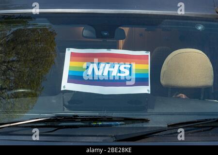 10. April 2020. Ein NHS-Poster in einer Autoscheibe, das das Fahrzeug zeigt, gehört einem Mitarbeiter des NHS. Während der Pandemie des Coronavirus Covid-19 von 2020 ist der Regenbogen zum Symbol der Unterstützung für Menschen geworden, die Solidarität mit den Beschäftigten des Gesundheitsdienstes an der Front zeigen wollen. Stockfoto