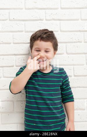 Der kleine Junge pickt sich mit dem Finger die Nase Stockfoto