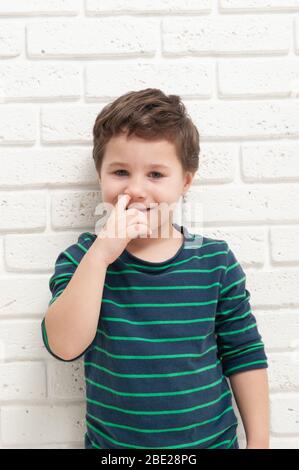 Der kleine Junge pickt sich mit dem Finger die Nase Stockfoto