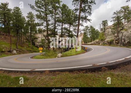 Eine Straße mit einer über- und Unterbrücke mit einem Tunnel durch einen Felsen. Stockfoto