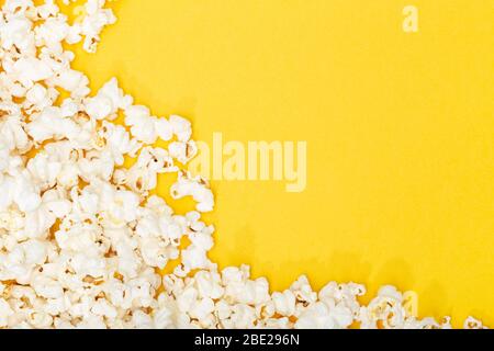 Popcorn auf gelbem Hintergrund. Film- oder TV-Hintergrund, Rahmen, Rahmen. Ansicht von oben Kopierbereich Stockfoto