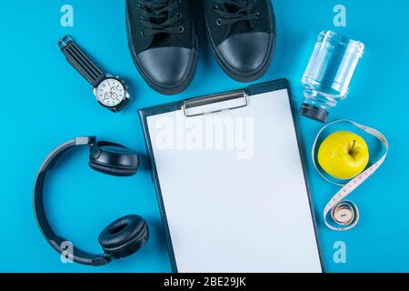 Diät-Plan. Weißes Blatt auf der Tablette zwischen den Flaschen mit Wasser, Uhr und Äpfeln mit Maßband auf einem hellblauen Hintergrund. Schlankheitskur und Stockfoto