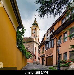 Das historische Gebäude des griechischen Tempels in Vac, Hungary.IT wurde im 18. Jahrhundert gebaut, ist heute eine Ausstellungshalle. Gewundene enge Kopfsteinpflaster Straße Stockfoto