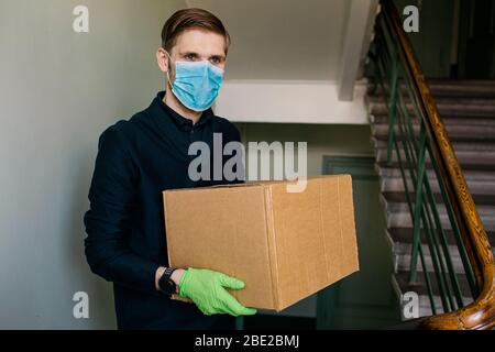 Lebensmittelgeschäft Lieferung Mann trägt medizinische Handschuhe und Gesichtsmaske. Online-Einkauf und Lieferung für Lebensmittel, Wein und Lebensmittel. Selbstquarantäne während Covid-19 Stockfoto