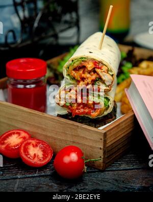 Hähnchenwickel in Fladenbrot eingetaucht in Ketchup Stockfoto