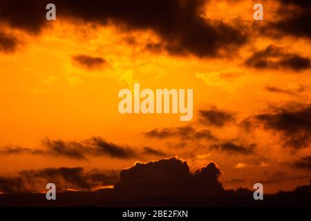 Schöner Sonnenuntergang mit verschiedenen orange und gelben Wolken in der goldenen Stunde. Schöne Landschaft von einem goldenen bewölkten Himmel. Stockfoto