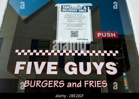 Watford, Großbritannien. 11. April 2020. Ein Schild im Fenster zeigt an, dass die Restaurants von Five Guys, einem Burger-Restaurant, am Ostersamstag im Einkaufszentrum Watford geschlossen werden, während die Coronavirus-Pandemie (COVID19) andauert. Take Away- und Delivery Services bleiben in Betrieb. Kredit: Stephen Chung / Alamy Live News Stockfoto