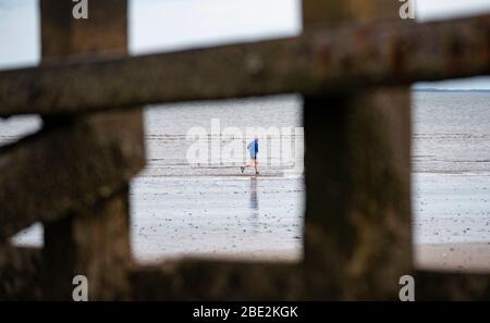 Portobello, Edinburgh. Schottland, Großbritannien. 11 April 2020. Am Osterwochenende am Samstagmorgen waren die Besucher draußen am Portobello Strand außerhalb von Edinburgh trainieren und spazieren gehen. Der beliebte Strand und die Promenade sind sehr ruhig und die Leute üben eine richtige soziale Distanz aus. Iain Masterton/Alamy Live News Stockfoto