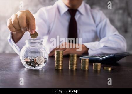 Business man oder Bankier setzen Münze in Glas und gestapelt Geld, um Investitionen, Finanzen und Einkommen Konzept zu sparen Stockfoto