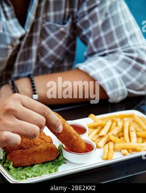 Mann taucht Hühnchen Nugget in süße Chili-Sauce Stockfoto