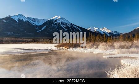 Schneebedeckter Sundance Peak und Tannenbäume spiegeln sich in den stillen Gewässern von Vermillion Lakes, Banff National Park, Banff, Alberta, Kanada Stockfoto