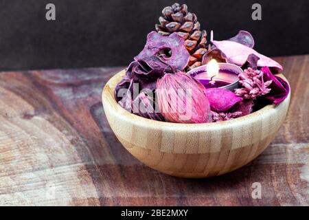 Pourple Teelicht und trocken Potpourri in einer Holzschale über einem Tisch mit schwarzem Hintergrund Stockfoto