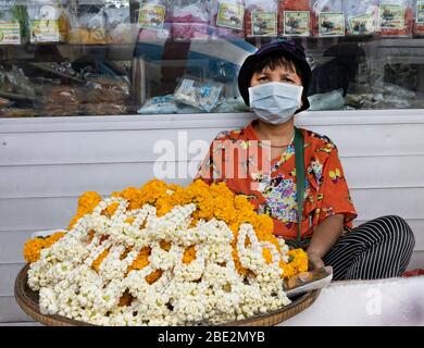 Bangkok, Thailand - 27. Februar 2020: Ein Blumenhändler, der eine Schutzmaske trägt, auf einer Straße in Bangkok. Stockfoto