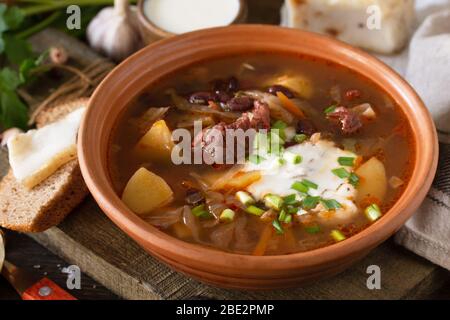 Das Konzept der gesunden Ernährung und Ernährung. Russische oder ukrainische Küche. Suppe mit Fleisch und Bohnen oder Borsch-Nahaufnahme mit saurer Sahne auf einem rustikalen Woo serviert Stockfoto