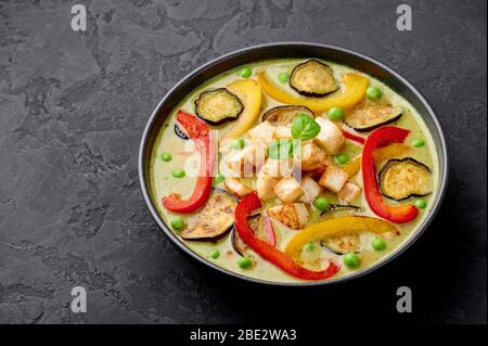 Vegetarische Thai Green Curry mit Tofu in schwarzer Schale auf dunklem Schiefergrund. Gemüse Green Thai Curry ist thailand Küche Gericht mit grünen Chilis Paste, Stockfoto