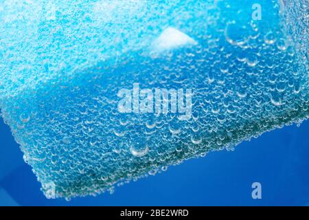 Blauer Spülschwamm, selektiver Fokus. Blasen, unter Wasser. Poröser Makroschwamm Stockfoto