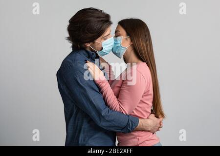 Romantische Quarantäne. Junges Paar Küssen Einander Mit Schützenden Medizinischen Masken Stockfoto