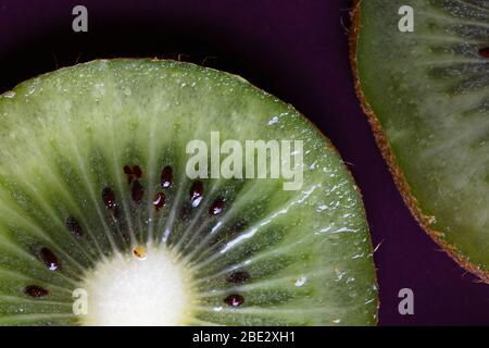 Ein fantastisches Stillleben Studio Detail Nahaufnahme von frischen leckeren geschnittenen Kiwi Früchte auf lila Platte , topview Stockfoto