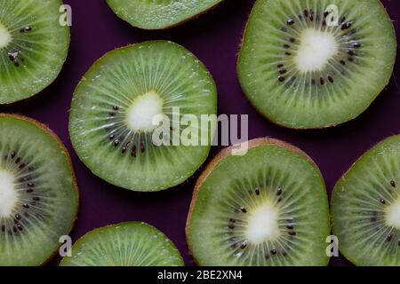 topview ist eine fantastische Fotokomposition aus frischen, leckeren, geschnittenen Kiwi-Früchten auf einem violetten Hintergrund Stockfoto