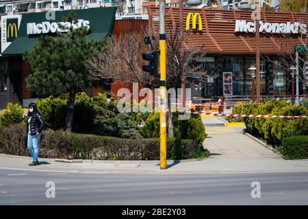 Frau mit Schutzmaske vor dem geschlossenen für normale Geschäfte McDonalds Fast-Food-Restaurant, das nur Drive-in- oder Drive-Thru-Essen zum Mitnehmen erlaubt, aufgrund der Verbreitung der Coronavirus-Pandemie von Covid-19 in Sofia, Bulgarien. Kredit: Ognyan Trifonov / Alamy Stockfoto