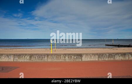 Portobello Promenade, Edinburgh, Schottland, Großbritannien. April 2020. Temperatur von 16 Grad mit voller Sonne am Nachmittag nach einem bewölkten Start. Am Ostersamstag ein sehr ruhiger Strand am dritten Wochenende der Coronavirus Lockdown. Auf der Promenade eine mit Kreide geschriebene Botschaft, die die Porty-Leute während der Coronavirus-Pandemie beglückwünscht. Quelle: Arch White / Alamy Live News. Stockfoto