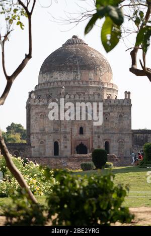 Neu Delhi, Indien - 17. März 2020: Altes Bara Gumbad Grab Lodi Gärten Neu Delhi Indien, mit Baumblättern im Vordergrund Stockfoto