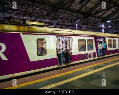 Mumbai, Indien - 26. Januar 2020 : Unidentifizierte Passagiere stehen an der Tür des fahrenden Nahzugs in Mumbai Stockfoto