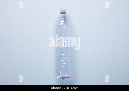 Eine minimalistische leere Plastikflasche, in der Mitte des Bildes, vor einem pastellblauen Hintergrund, flaches Lay, Studioaufnahme Stockfoto