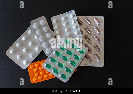 Eine Menge von farbigen Pillen in Blasen auf schwarzem Hintergrund. Gesundheitskonzept und medizinisches Konzept. Horisontalrahmen, Nahaufnahme. Stockfoto