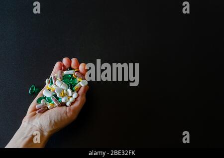 Viele verschiedene Medikamente, Pillen, Tabletten, Kapseln in der Frau Hand auf schwarzem matten Hintergrund. Makro-Foto mit selektivem Fokus. Medizinische Apotheke Stockfoto