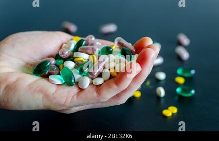 Viele verschiedene Medikamente, Pillen, Tabletten, Kapseln in der Frau Hand auf schwarzem matten Hintergrund. Makro-Foto mit selektivem Fokus. Medizinische Apotheke Stockfoto