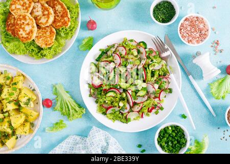 Frischer Gemüsesalat mit Rettich, Salat und Gurke, gekochte neue Kartoffeln mit Butter, Dill und grüne Zwiebel und gebratene Hähnchenfleisch-Koteletts zum Mittagessen Stockfoto