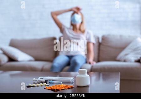 Frau drückt Hand an Kopf, sitzt auf dem Sofa Stockfoto