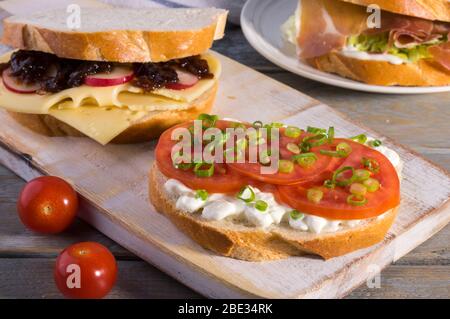 Verschiedene Fleisch- und vegetarische Sandwiches auf einem rustikalen Schneidebrett. Stockfoto