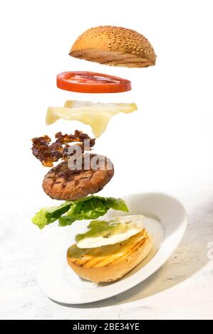 Burger Zubereitung geschnittene Zutaten schweben auf weißem Hintergrund Stockfoto