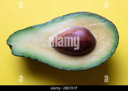 Nahaufnahme einer frisch geschnittenen Avocado auf gelbem Hintergrund, Draufsicht Stockfoto