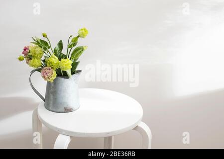 Bouquet von grünen und rosa Frottee Lisianthus und Eukalyptus Zweige in einem Zinnkrug auf einem weißen Stuhl. Brautstrauß Stockfoto