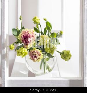 Bouquet von grünen und rosa Terry Lisianthus und Eukalyptus Zweige in einer transparenten runden Vase auf weißem Hintergrund. Brautstrauß Stockfoto