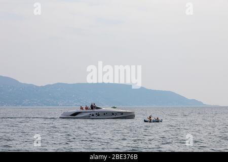 Ein großes Motorboot fährt langsam an einem 2-Mann-Kanu am Gardasee vorbei. Stockfoto