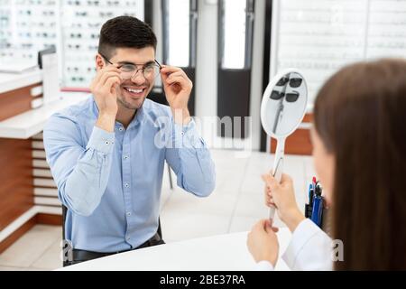 Optometriker helfen Kerl, Korrektur Brille zu wählen Stockfoto