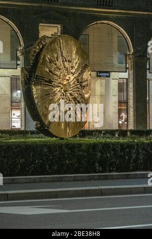 Disco, eine Bronzeskulptur von Arnaldo Pomodoro in Filippo Meda Sqaure , Innenstadt von Mailand, bei Nacht, während der Coronavirus-Sperre. 16. MÄRZ 2020 Stockfoto