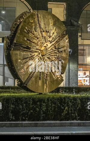 Disco, eine Bronzeskulptur von Arnaldo Pomodoro in Filippo Meda Sqaure , Innenstadt von Mailand, bei Nacht, während der Coronavirus-Sperre. 16. MÄRZ 2020 Stockfoto