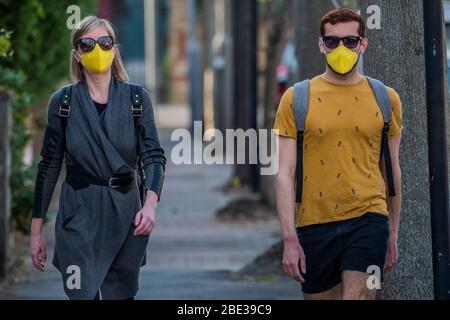 London, Großbritannien. April 2020. Ein Paar in passenden Masken geht zu den Mini-Sainsburys an der Tankstelle - die 'Sperre' geht weiter für den Ausbruch des Coronavirus (Covid 19) in London. Kredit: Guy Bell/Alamy Live News Stockfoto