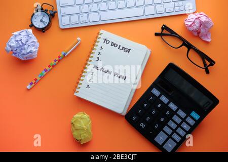 Hohe Winkelansicht der To-Do-Liste auf Notizblock auf orangefarbenem Hintergrund. Stockfoto