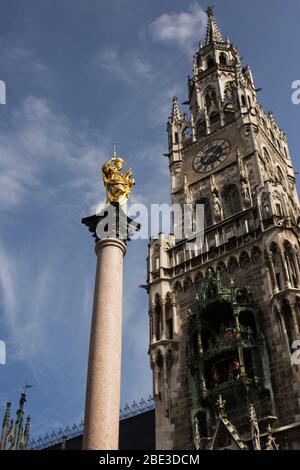 Die Mariensäule vor dem Neuen Rathaus auf dem Marienplatz in München, mit Uhrturm und Glockenspiel. Stockfoto